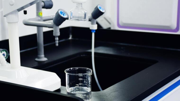 Ein Messbecher steht auf einem Labortisch mit Armaturen